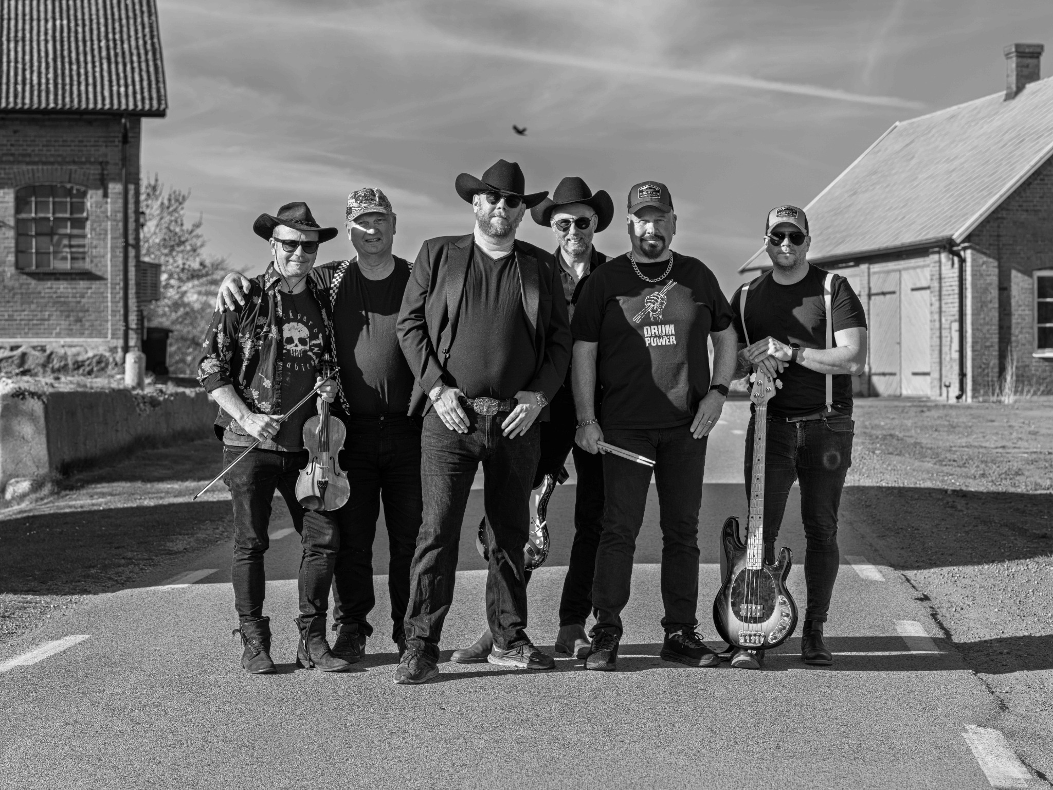 Barkland Bands sex musiker samlade på en gårdsplan i svartvitt