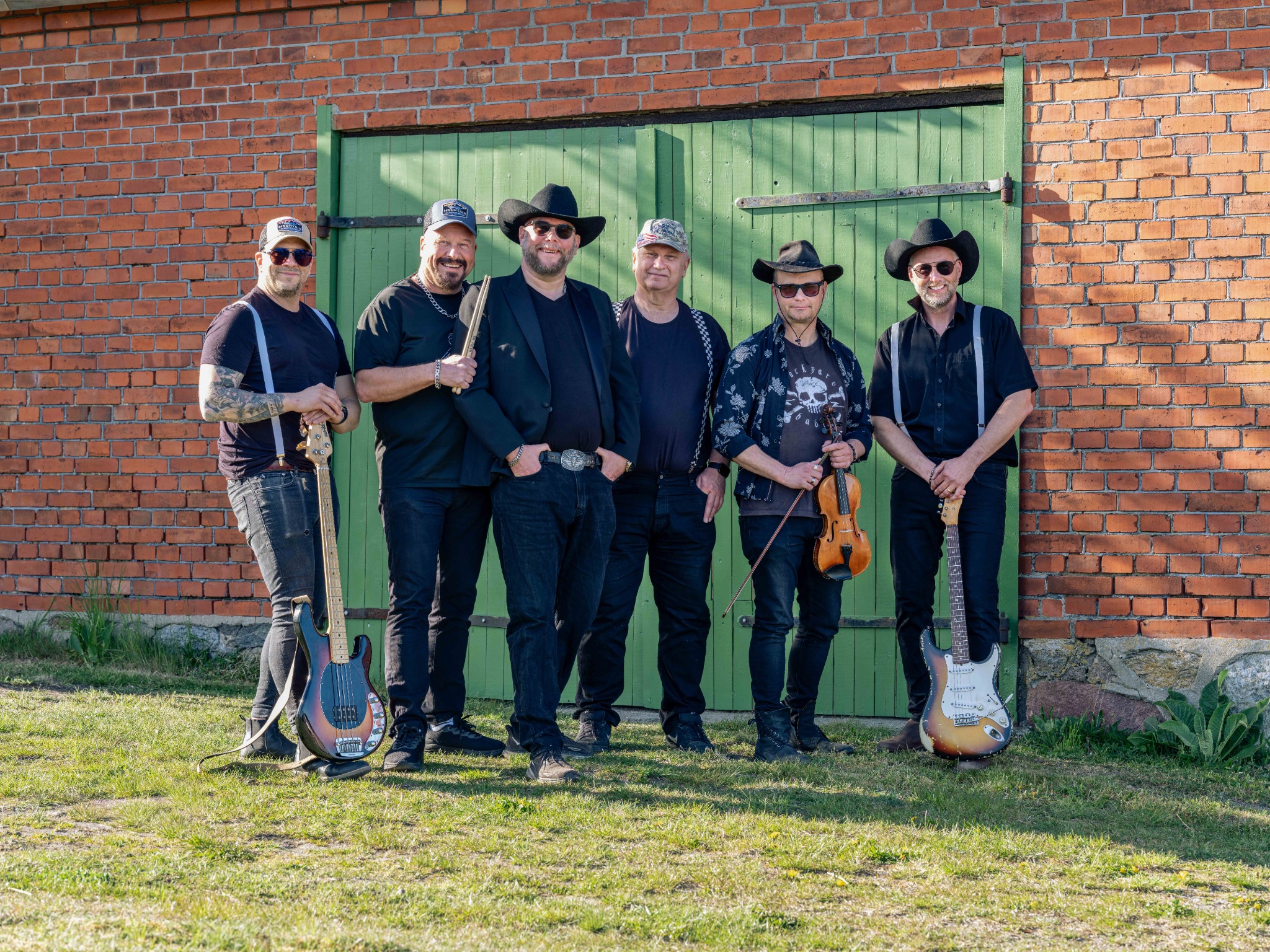 Barkland Bands sex musiker framför en grön ladugårdsport